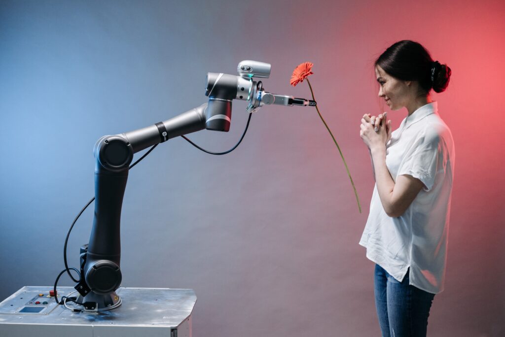 A robotic arm offers a flower to a woman in a display of technology and human connection.